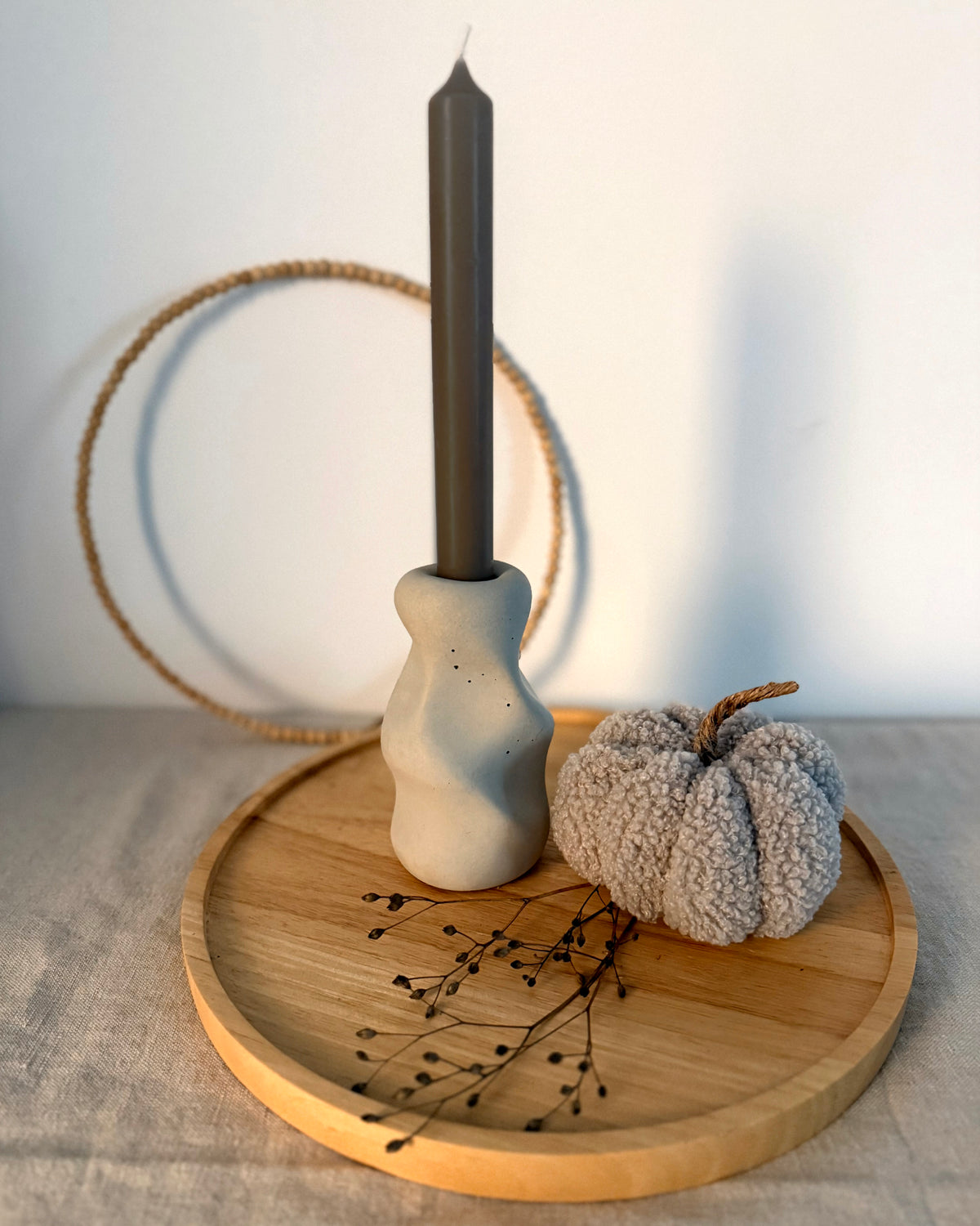 Kerzenständer Organic mit dunkler Stabkerze auf Holztablett neben einem Stoffkürbis