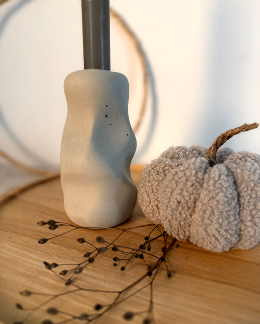 Nahaufnahme des Kerzenständers Organic mit sichtbaren Poren und dunkler Stabkerze